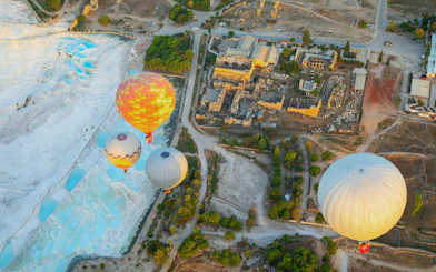 Aerial view of hot air balloons over Pamukkale travertines in Denizli at sunrise.