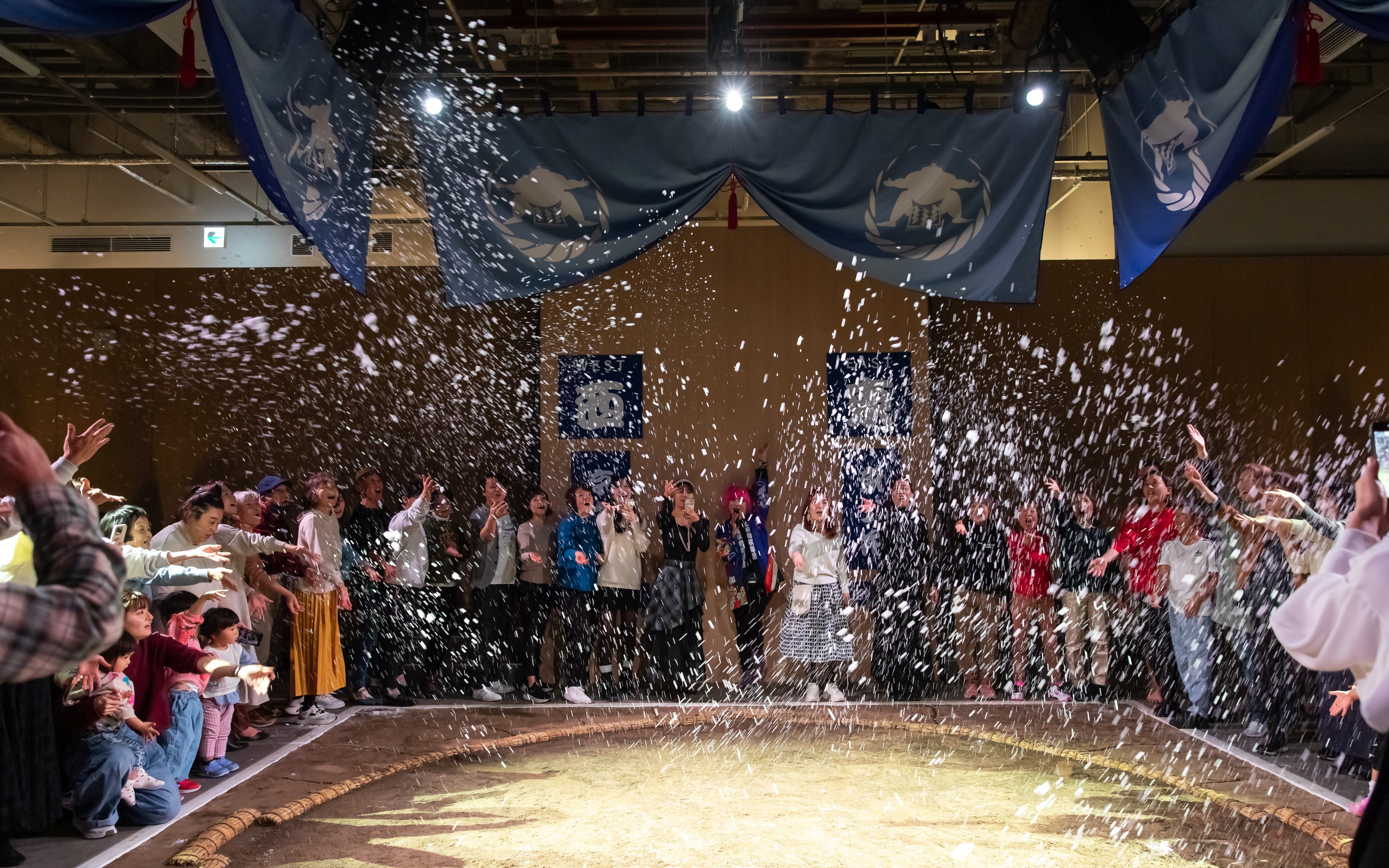 Audience enjoying Kyoto sumo entertainment show with confetti.