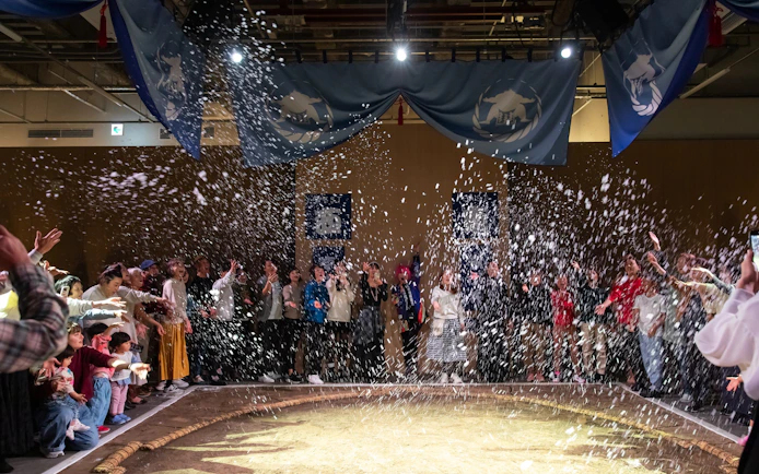 Audience enjoying Kyoto sumo entertainment show with confetti.