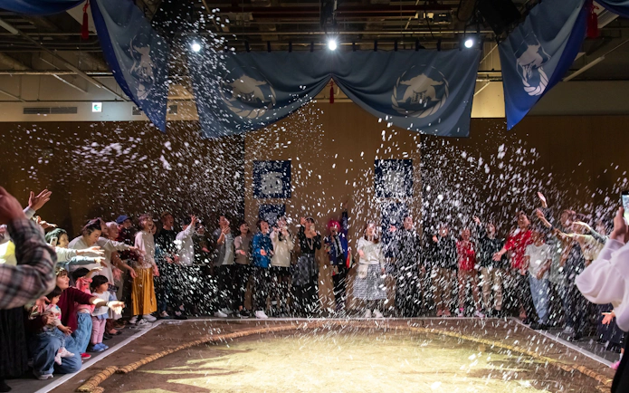 Audience enjoying Kyoto sumo entertainment show with confetti.
