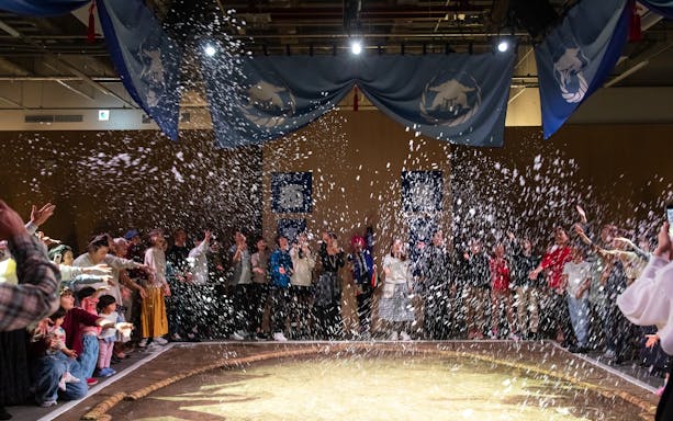 Audience enjoying Kyoto sumo entertainment show with confetti.