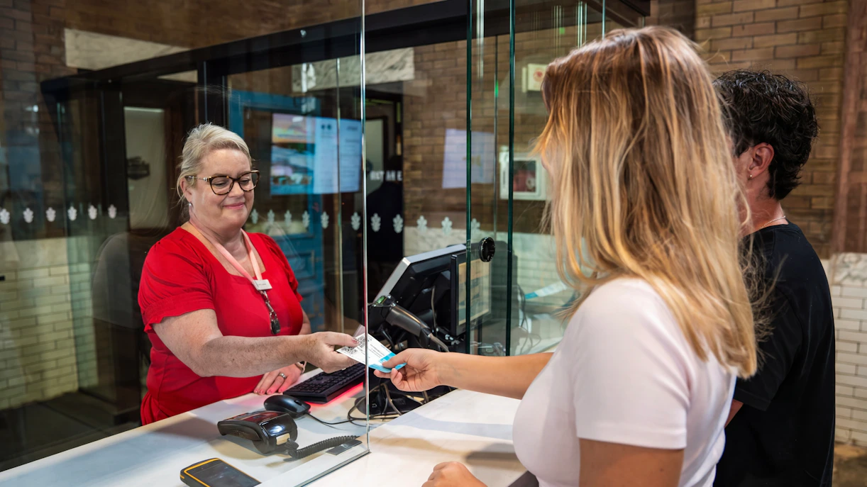 Visitor receiving ticket at Niagara Parks Power Station entrance during daytime.