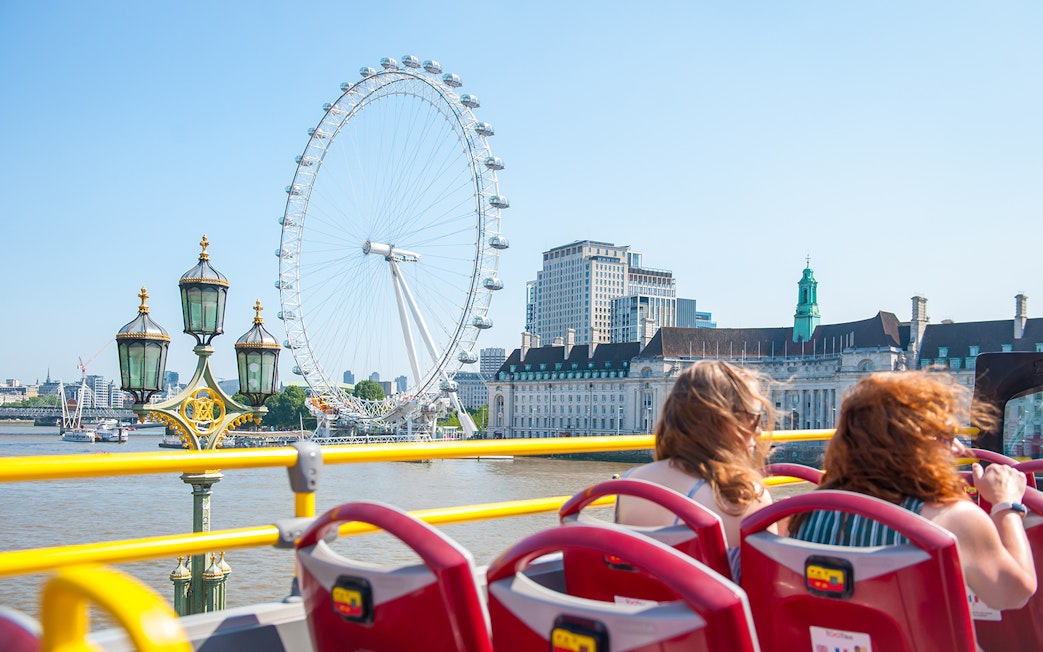 Open-top bus tour with children viewing the London Eye and River Thames.