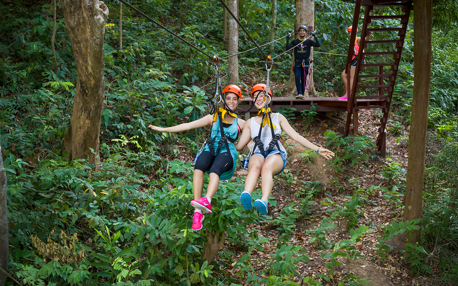 Girls ziplining through forest at Hanuman World, Thailand.