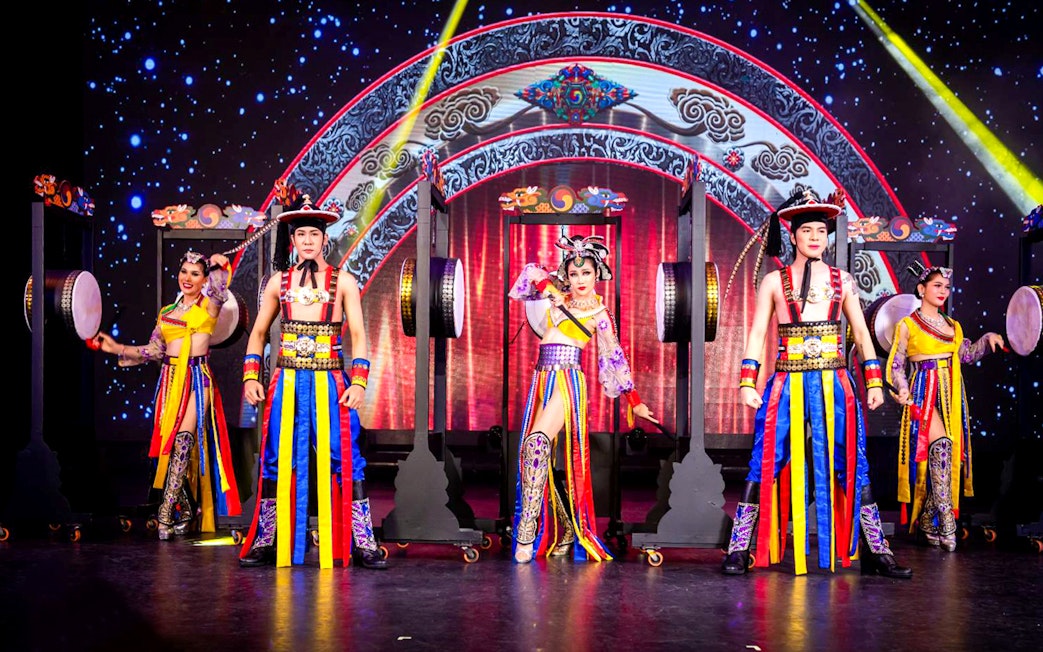 Performers in colorful costumes on stage at Simon Cabaret Show, Phuket.