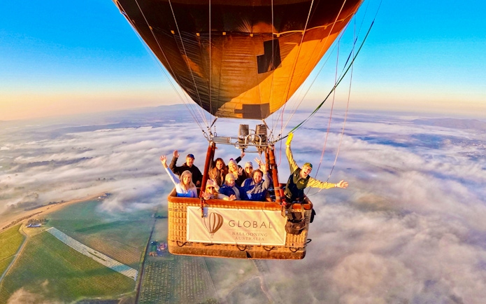 Hot air balloon with passengers over Yarra Valley at sunrise, Australia.