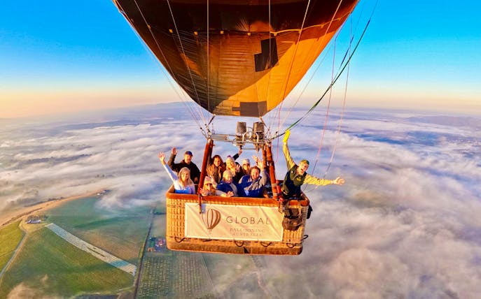 Hot air balloon with passengers over Yarra Valley at sunrise, Australia.