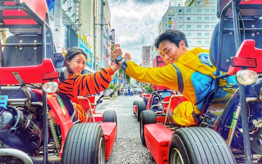 Street go-karting in Okinawa with participants in colorful costumes, high-fiving on a city road.