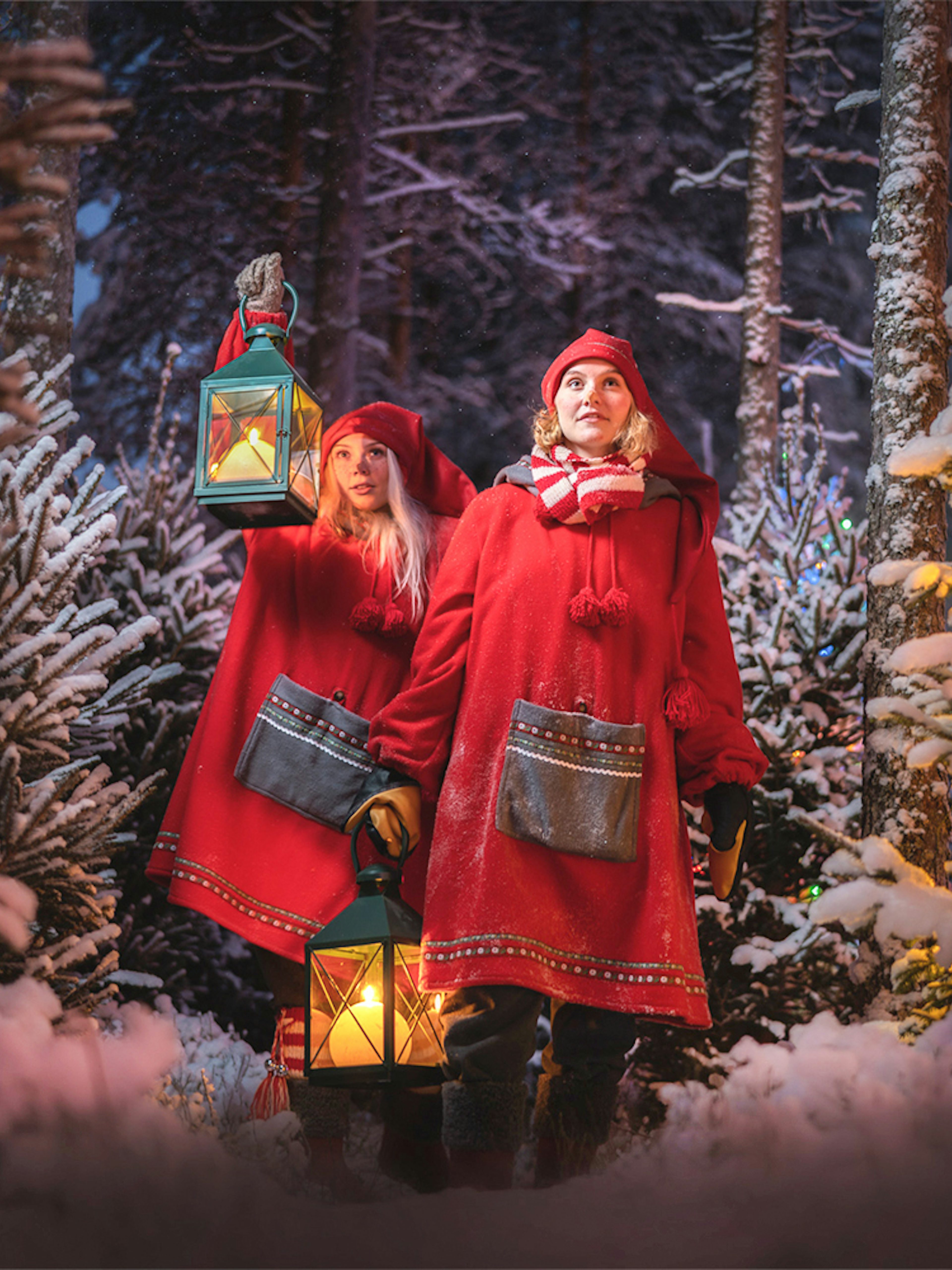 Elves in red cloaks holding lanterns in snowy forest at Elf Hat Academy, Santa's Village.