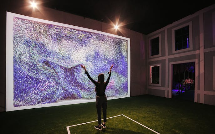 Person admiring digital art at Monet’s Garden Immersive Exhibition.