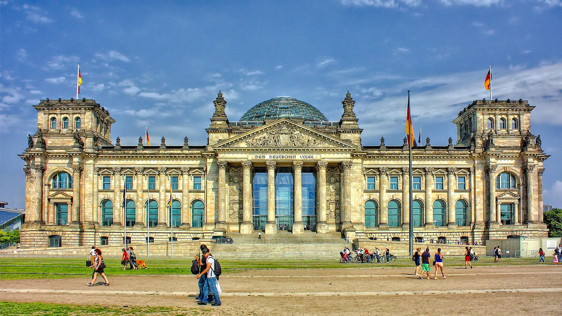 Reichstag building in Berlin, a key WWII historical site, with visitors walking nearby.