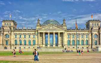 Reichstag building in Berlin, a key WWII historical site, with visitors walking nearby.