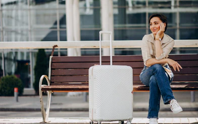 Traveler sitting on bench with suitcase at Marrakech Airport for hotel transfer.