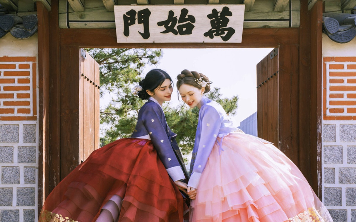 Two people in traditional hanbok at Gyeongbokgung Palace, Seoul.