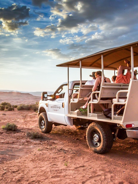 Tour group in open-air vehicle exploring Secret Antelope Canyon and Horseshoe Bend at sunset.