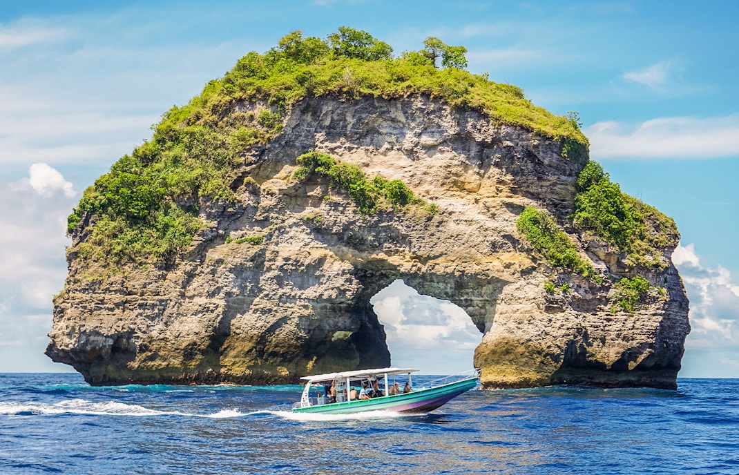 Speedboat with tourists approaching Nusa Penida Island, Bali, showcasing unique coastal views.