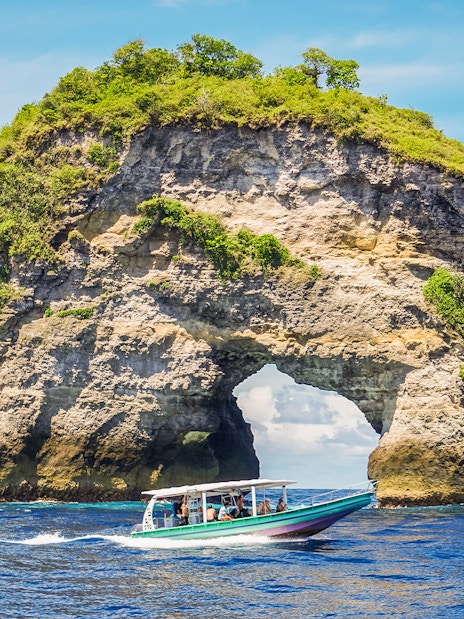 Speedboat with tourists approaching Nusa Penida Island, Bali, showcasing unique coastal views.