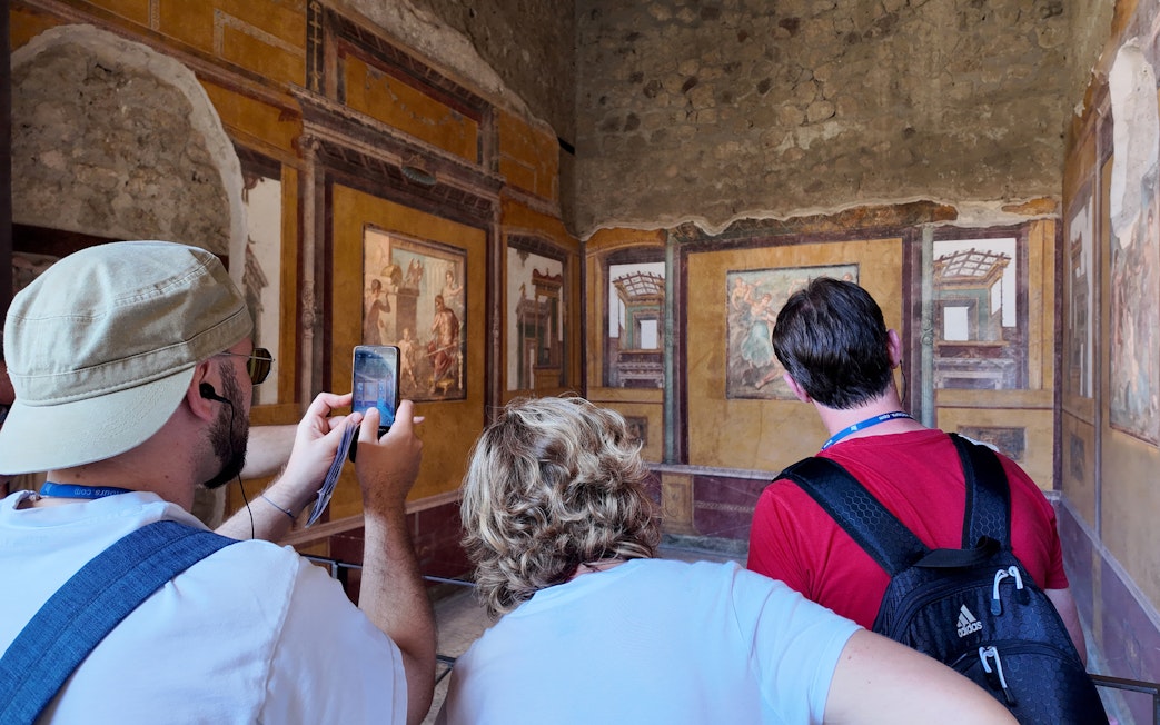 Visitors observing frescoes inside the House of Vettii, Pompeii.
