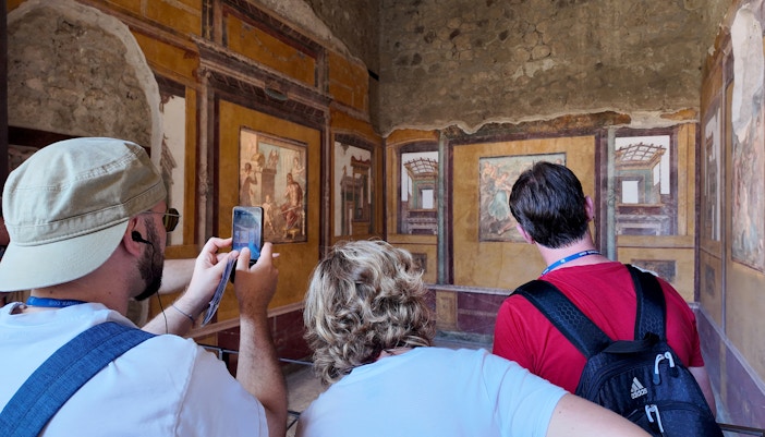 Visitors observing frescoes inside the House of Vettii, Pompeii.
