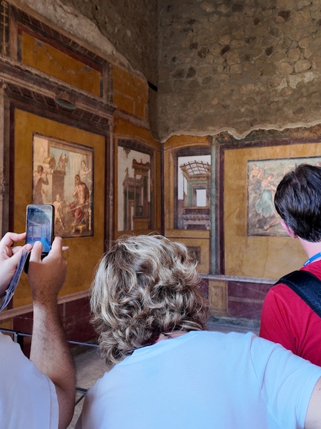 Visitors observing frescoes inside the House of Vettii, Pompeii.