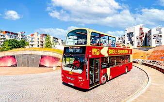 Edinburgh hop-on hop-off bus near modern architecture.