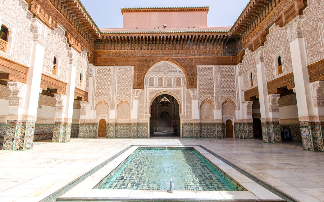 Ben Youssef Madrasa courtyard with intricate tilework and central reflecting pool in Marrakech.