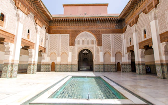 Ben Youssef Madrasa courtyard with intricate tilework and central reflecting pool in Marrakech.
