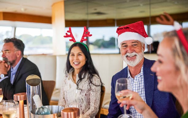 People enjoying a festive lunch on a Christmas Day cruise in Sydney.