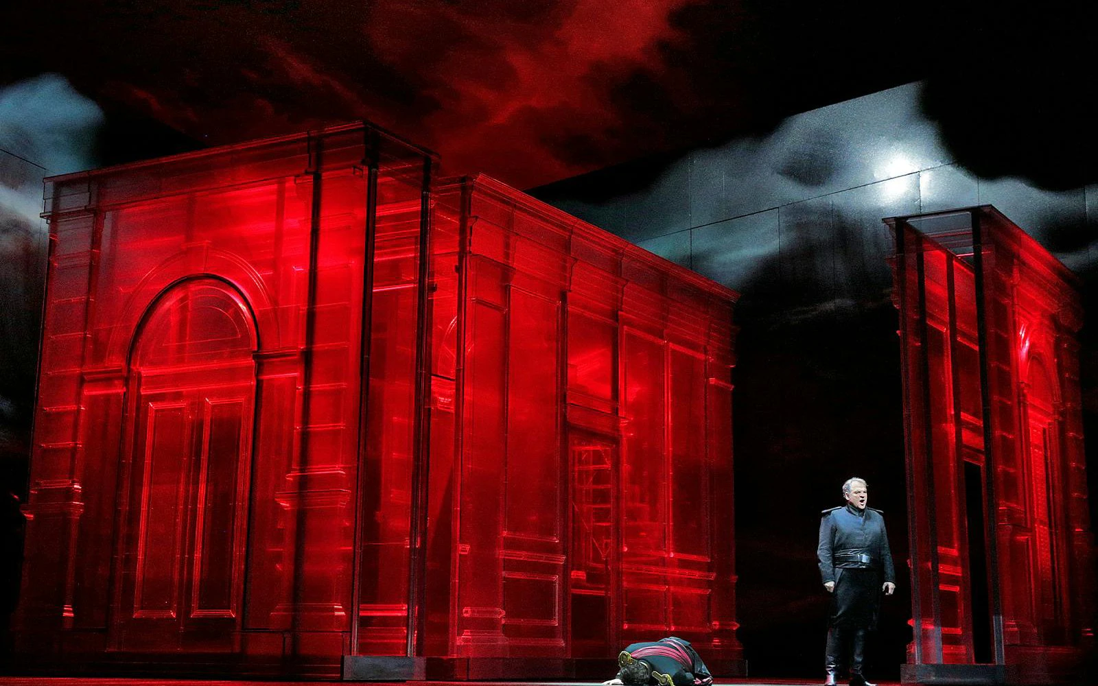 Otello performance on Broadway with actor on stage beside red architectural set.