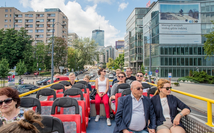 Passengers on an open-top bus tour in Warsaw city center, Poland.