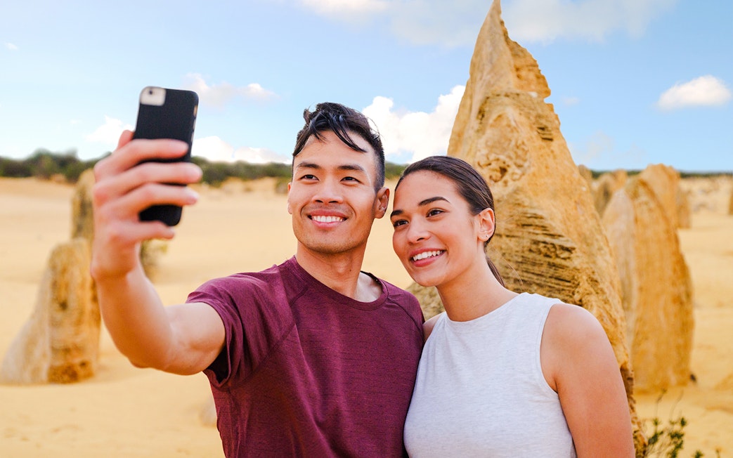 Tourists taking a selfie at Pinnacles Desert during sunset tour.