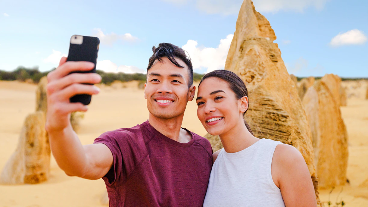 Tourists taking a selfie at Pinnacles Desert during sunset tour.