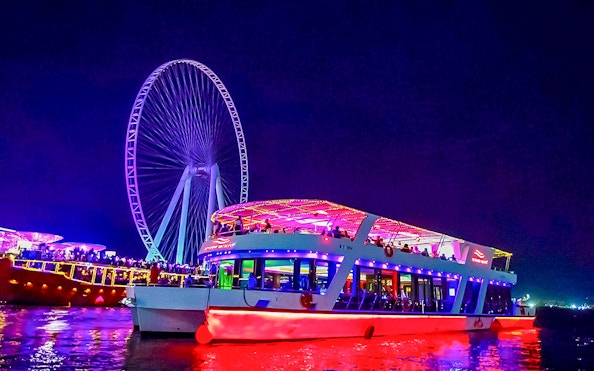 Dinner cruise with live music near illuminated Ferris wheel at night.