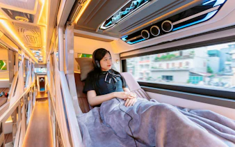 Sleeper cabin interior with passenger on Sapa–Hanoi–Noi Bai Airport shuttle.