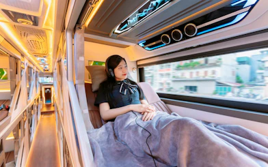 Sleeper cabin interior with passenger on Sapa–Hanoi–Noi Bai Airport shuttle.