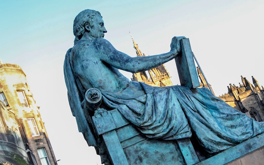 Statue of philosopher on Edinburgh’s Royal Mile with St Giles' Cathedral in background.