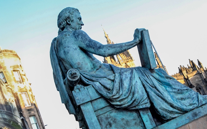 Statue of philosopher on Edinburgh’s Royal Mile with St Giles' Cathedral in background.