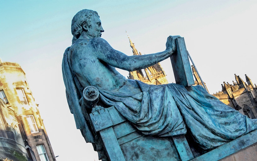 Statue of philosopher on Edinburgh’s Royal Mile with St Giles' Cathedral in background.
