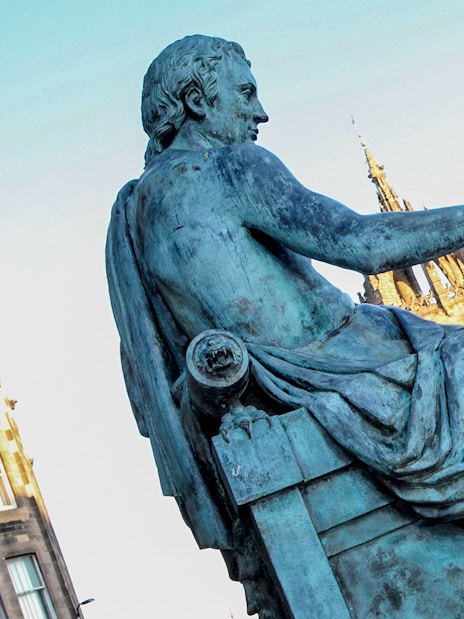 Statue of philosopher on Edinburgh’s Royal Mile with St Giles' Cathedral in background.