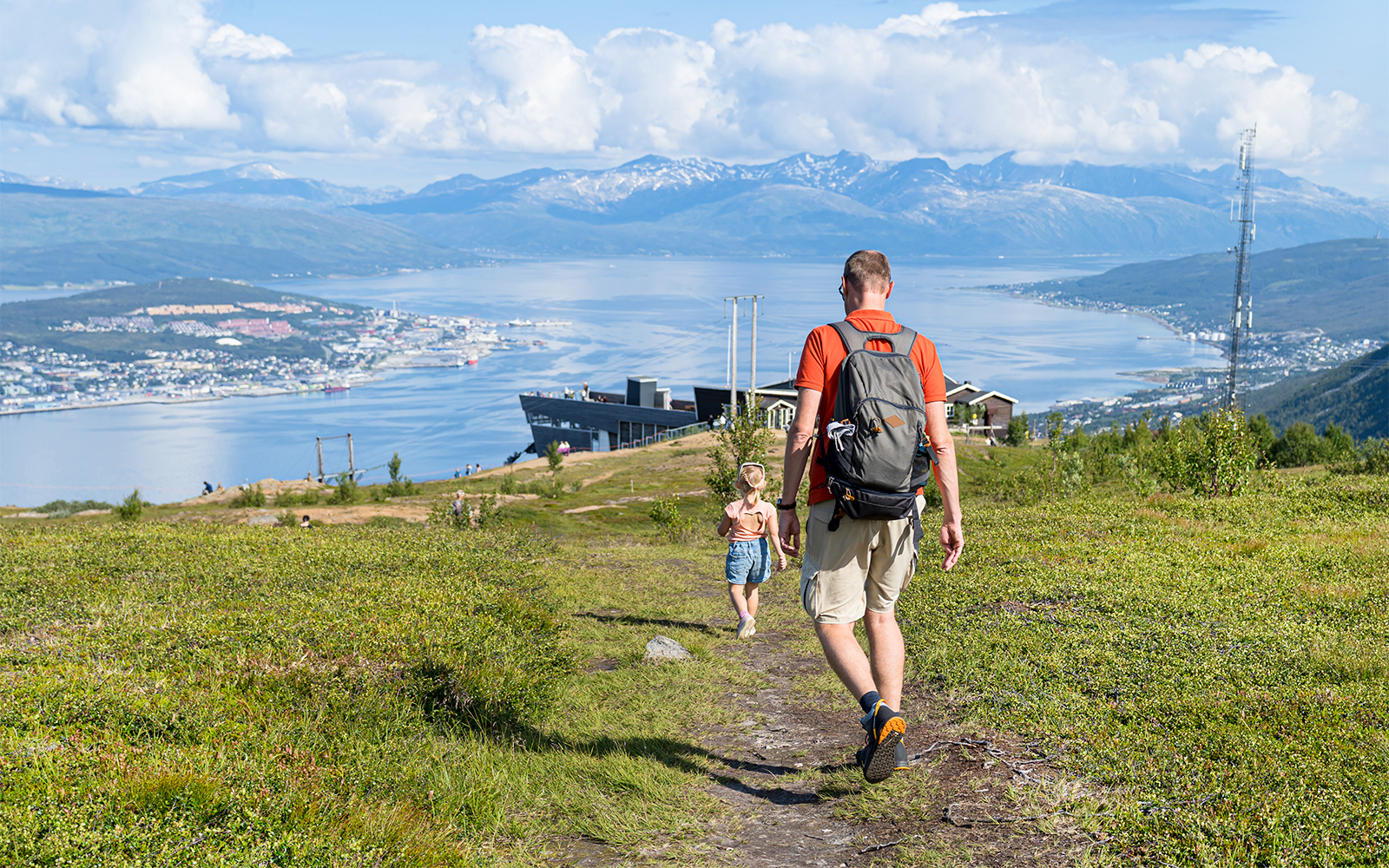 Father and daughter hiking with view of Tromsø city and fjord below.