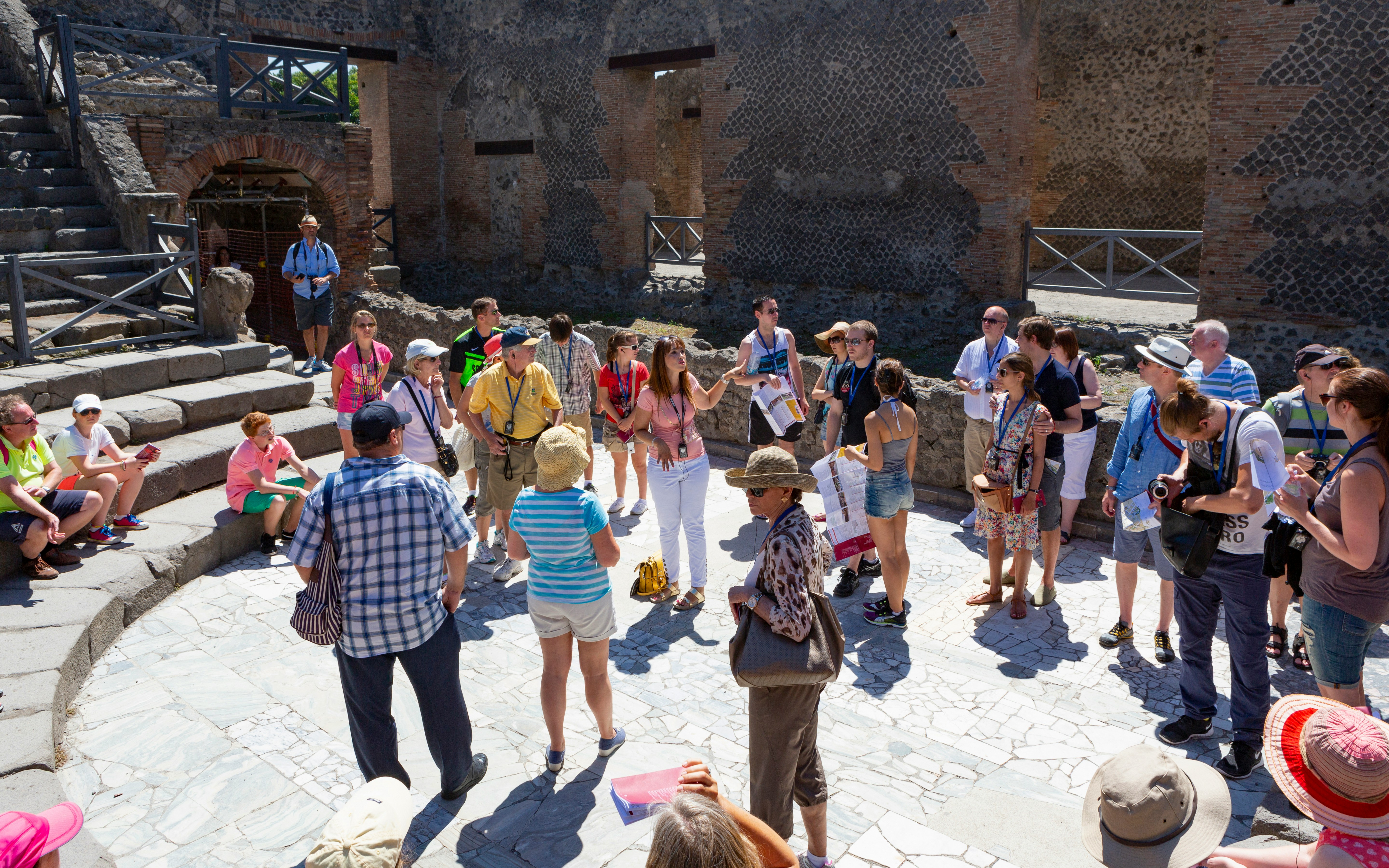 Tour guide with tourists at Pompeii Amphitheatre, Italy.