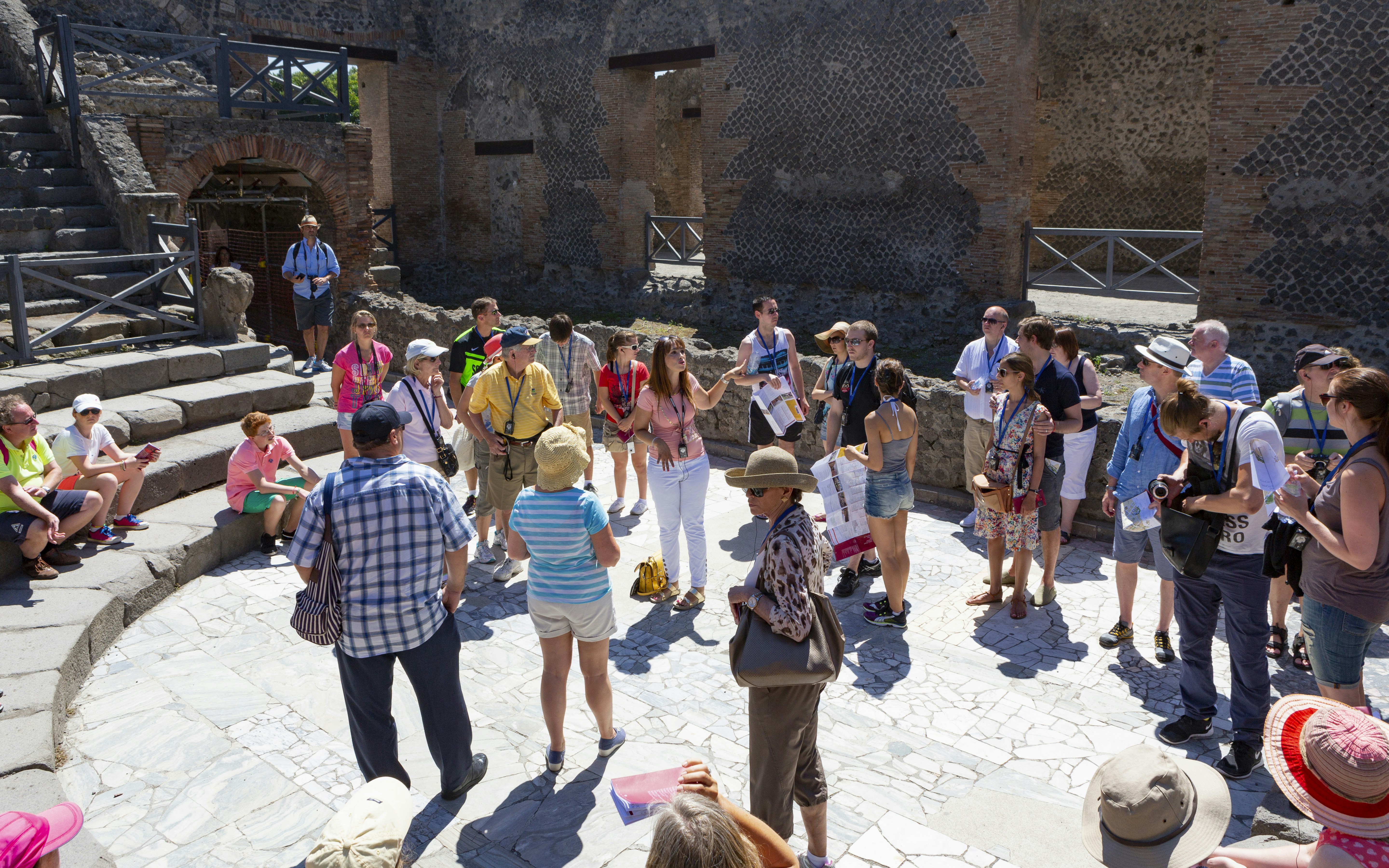 Tour guide with tourists at Pompeii Amphitheatre, Italy.