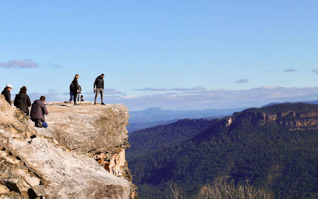 Visitors standing on Lincoln's Rock with Blue Mountains view, NSW, Australia.