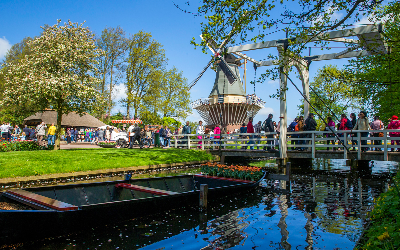 Keukenhof garden with windmill, bridge, and visitors in Lisse, Netherlands.