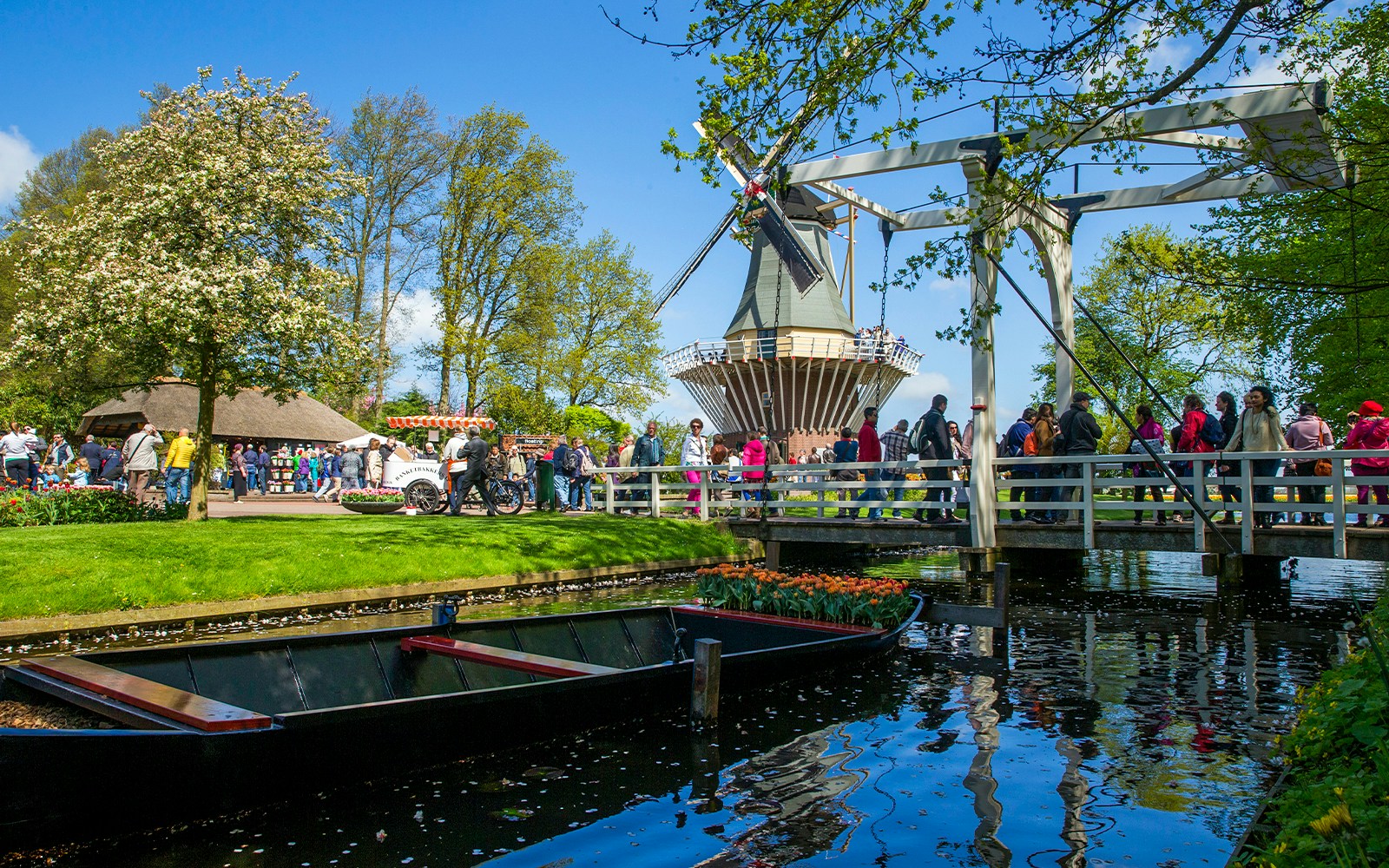 Keukenhof garden with windmill, bridge, and visitors in Lisse, Netherlands.