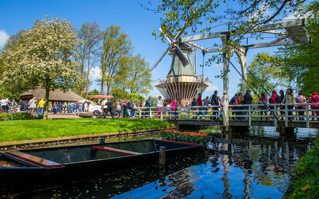 Keukenhof garden with windmill, bridge, and visitors in Lisse, Netherlands.
