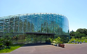 Glass conservatory at Shinjuku Gyoen, Tokyo, surrounded by greenery.