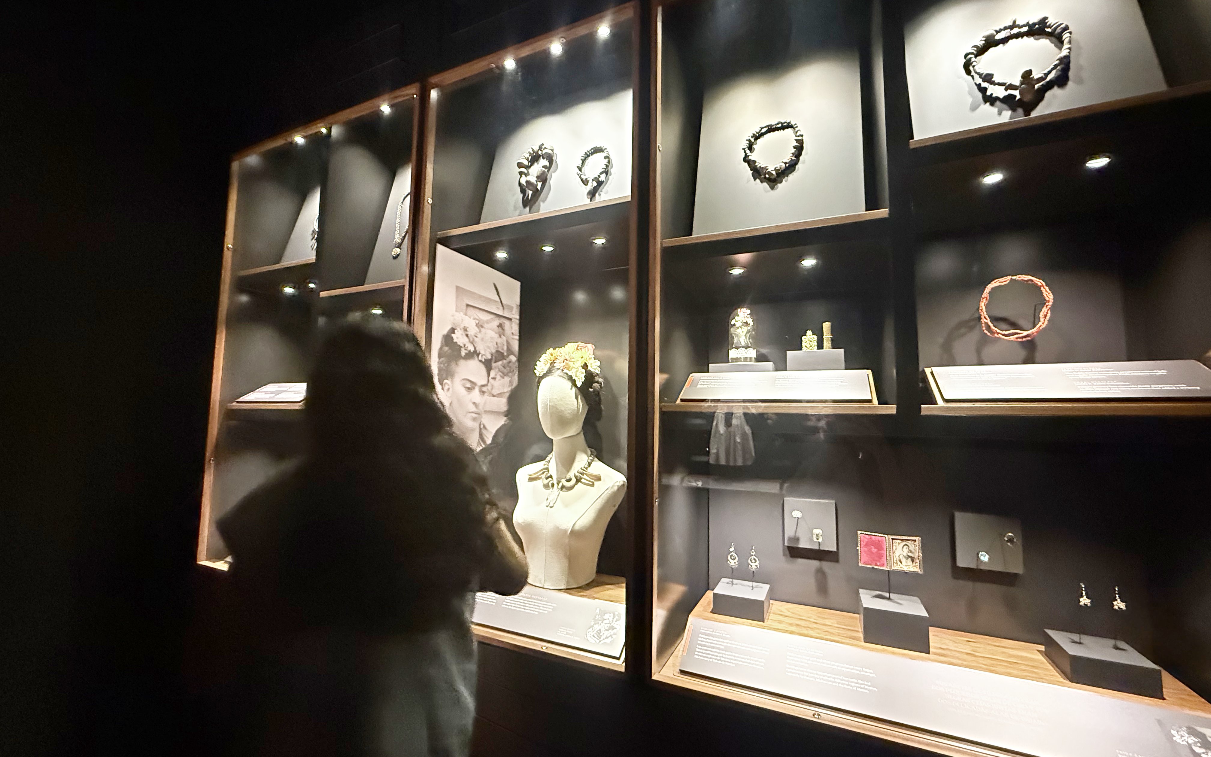 Jewelry display at Frida Kahlo Museum, La Casa Roja, with visitor observing exhibits.