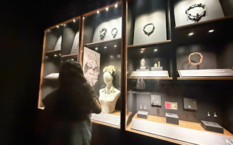 Jewelry display at Frida Kahlo Museum, La Casa Roja, with visitor observing exhibits.
