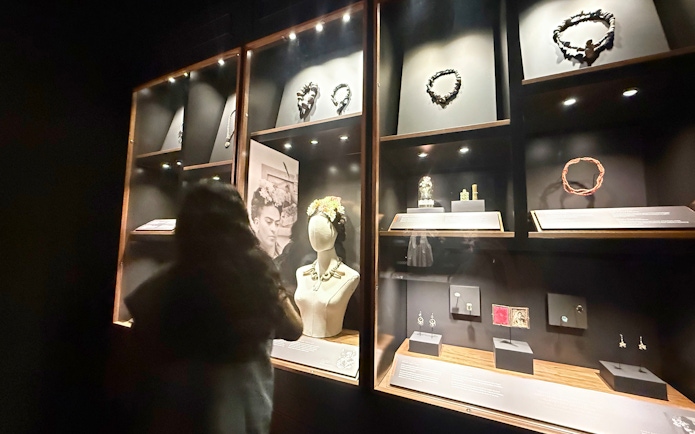 Jewelry display at Frida Kahlo Museum, La Casa Roja, with visitor observing exhibits.